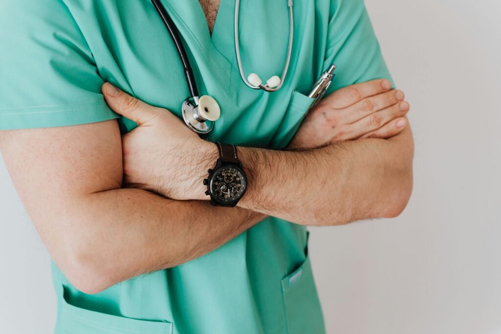 pexels photo 4021769 4021769 Close-up of a male doctor in scrubs with crossed arms and stethoscope on white background.